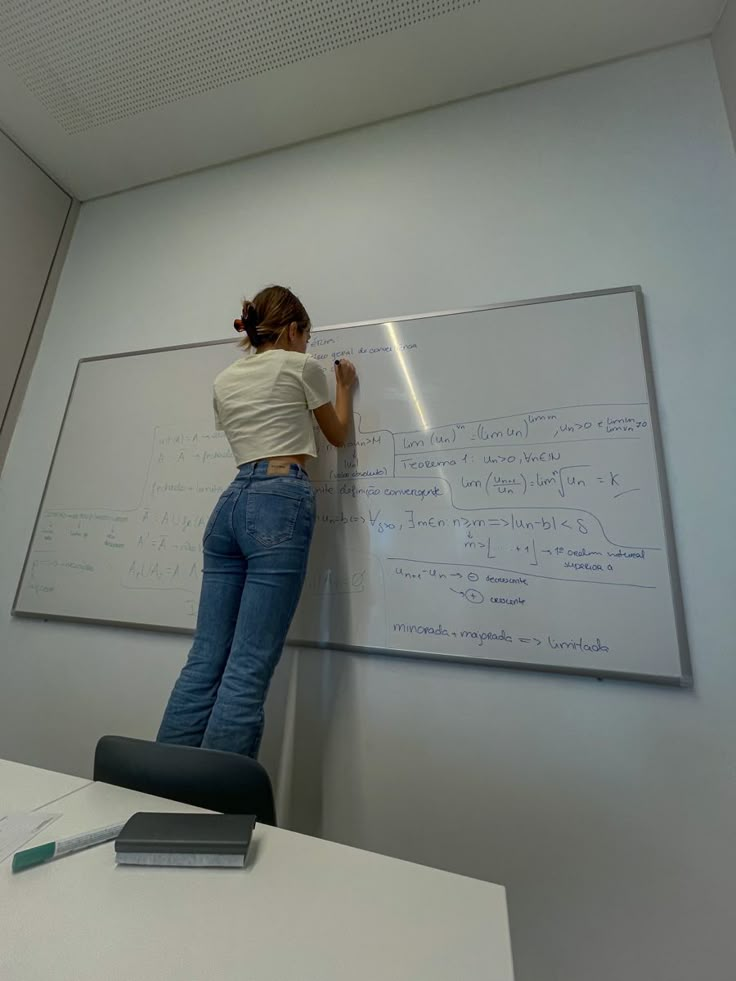 a woman writing on a whiteboard in an office