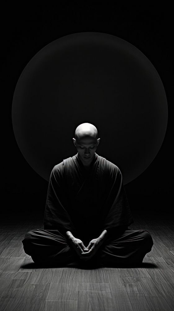 a man sitting in the middle of a dark room with his hands folded out to pray