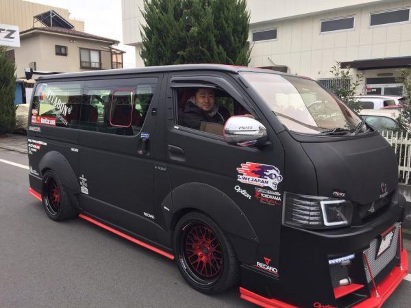 a black van with red rims driving down the street