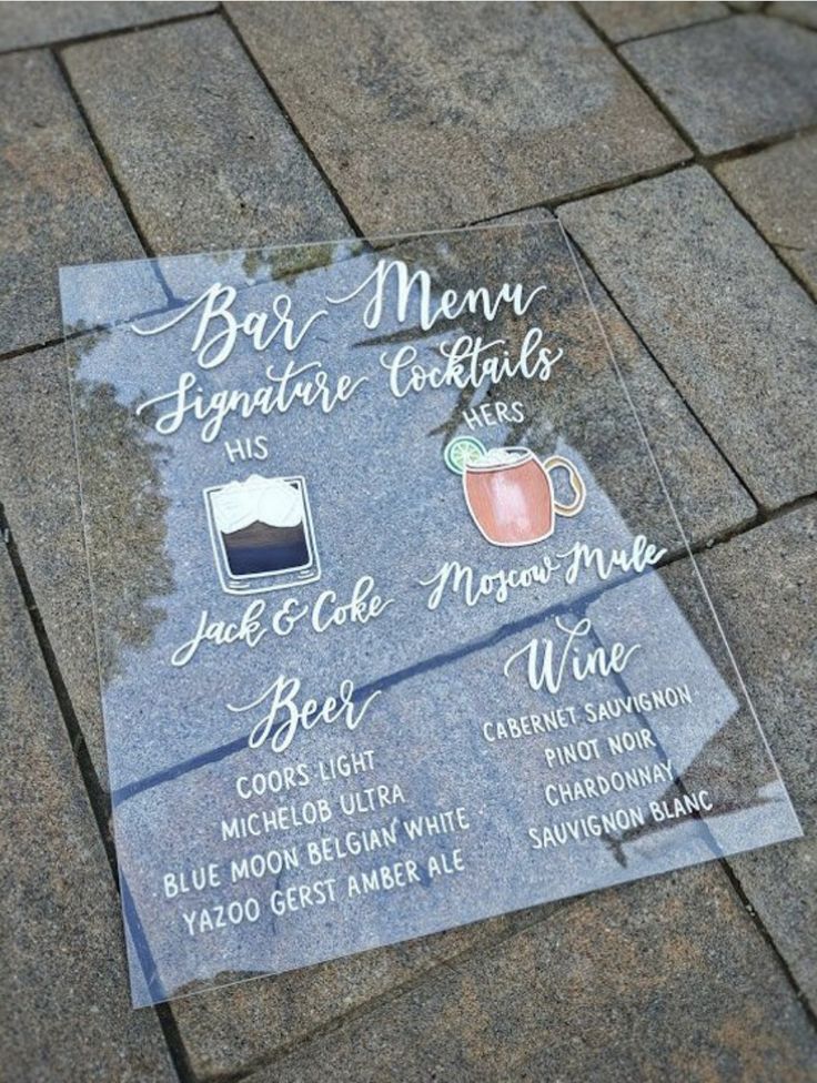 a glass plaque with different types of drinks on it sitting on the ground in front of a building