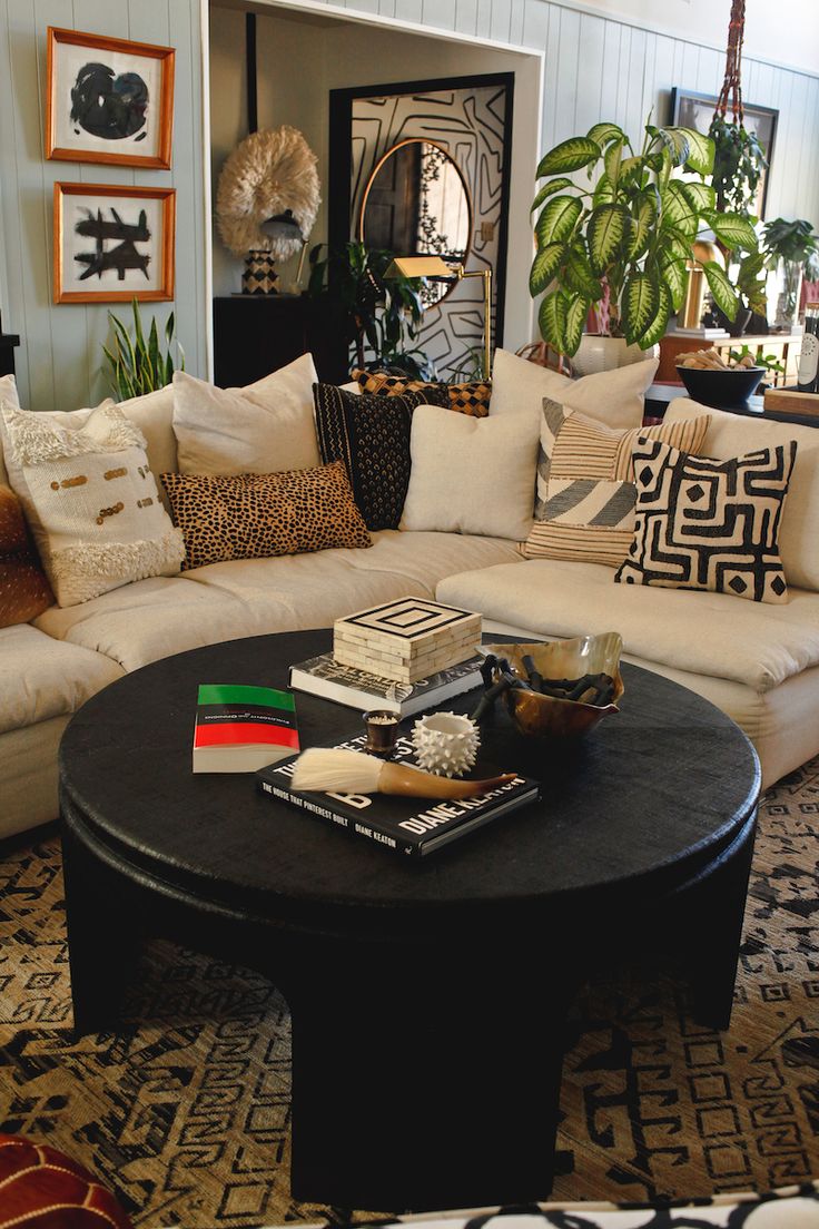 a living room filled with lots of furniture next to a large potted plant on top of a coffee table