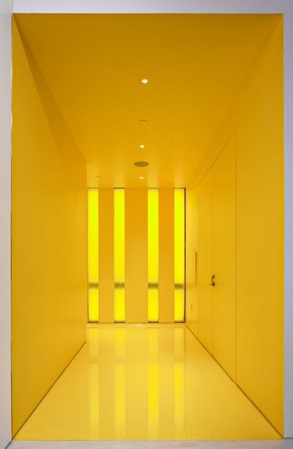 an empty room with yellow walls and flooring in the center is lit by bright lights