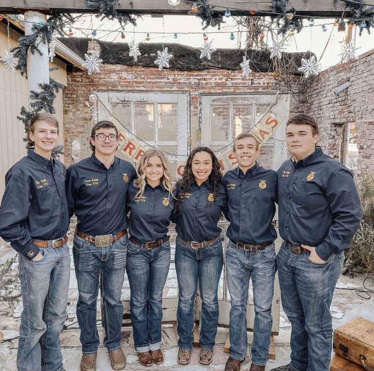 a group of young people standing next to each other in front of a building with christmas lights