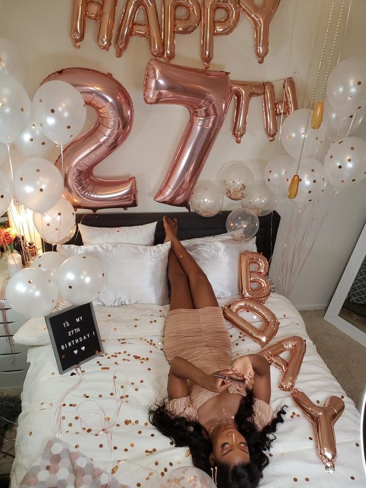 a woman laying on top of a bed in front of balloons and letters that spell happy 21st