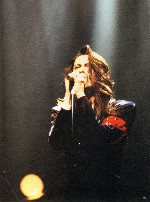 a woman with long hair holding a microphone in front of her face while standing on stage