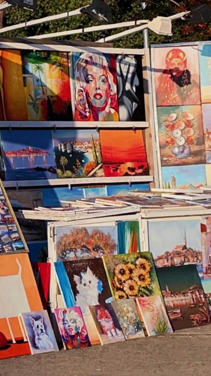 there are many paintings on display at this outdoor market