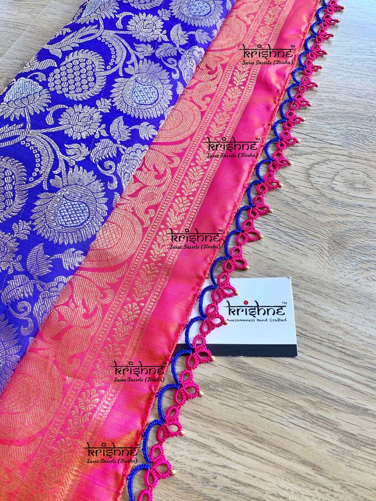 the purple and pink sari is on display in front of a wooden table with business cards