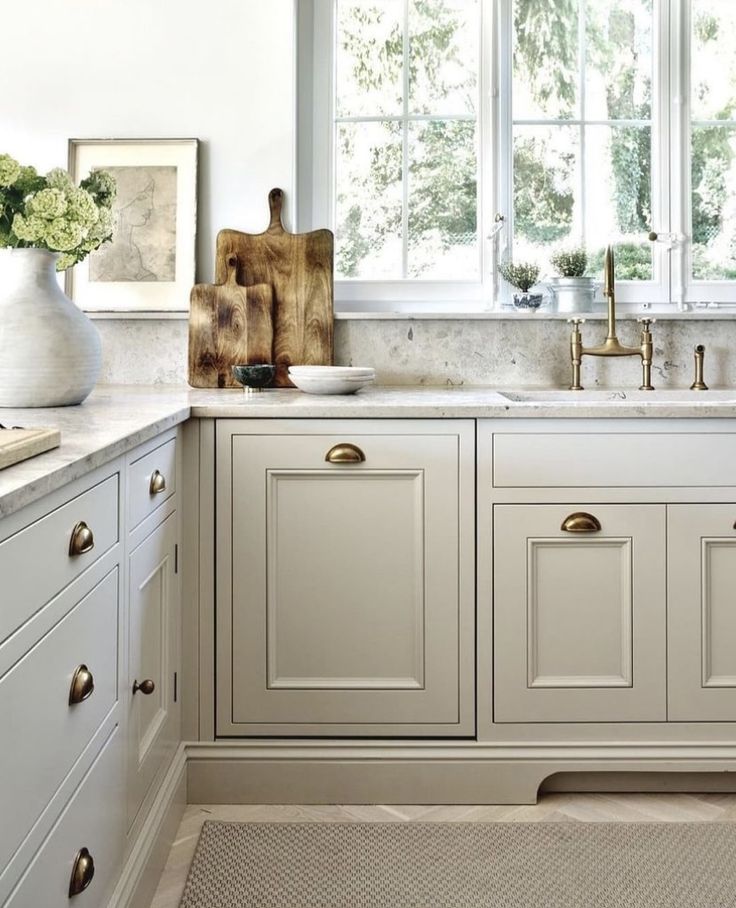 a kitchen with white cabinets and marble counter tops, along with brass pulls on the cabinet doors