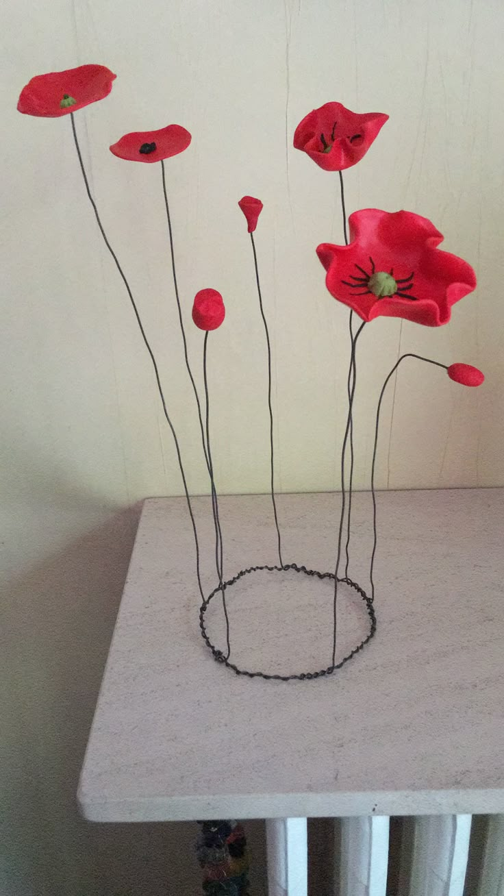 some red flowers sitting on top of a white table next to a radiator