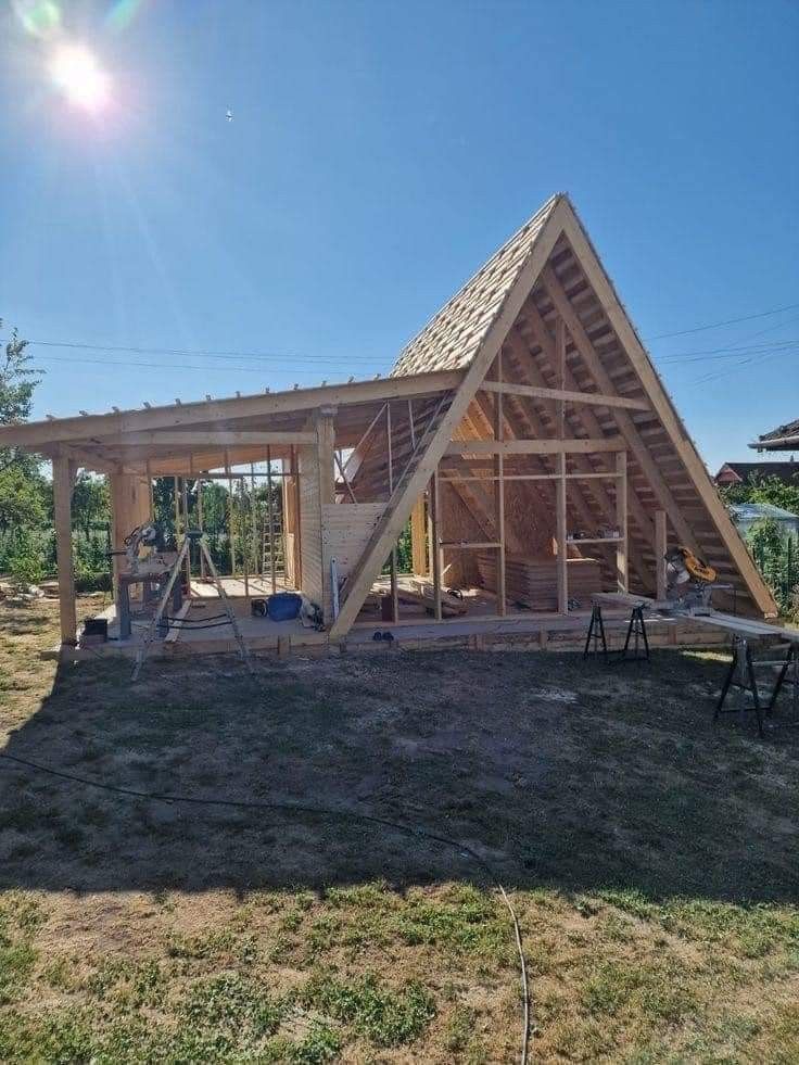 a frame house under construction in the middle of a field with sun shining on it