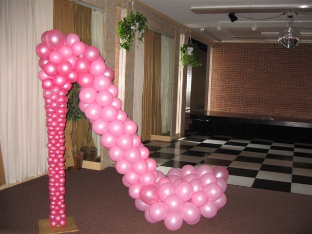 a balloon arch in the shape of a shoe with pink balloons attached to it, on top of a checkered floor