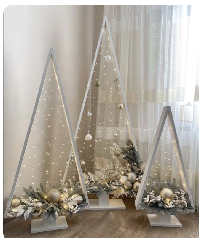 three white christmas trees in front of a window