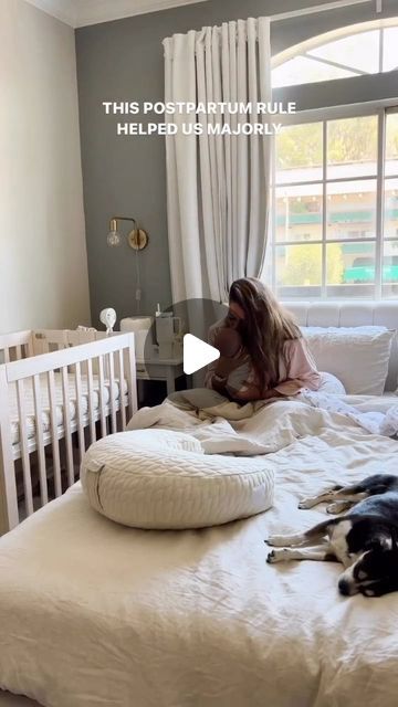 a woman laying on top of a bed next to a black and white dog in a room