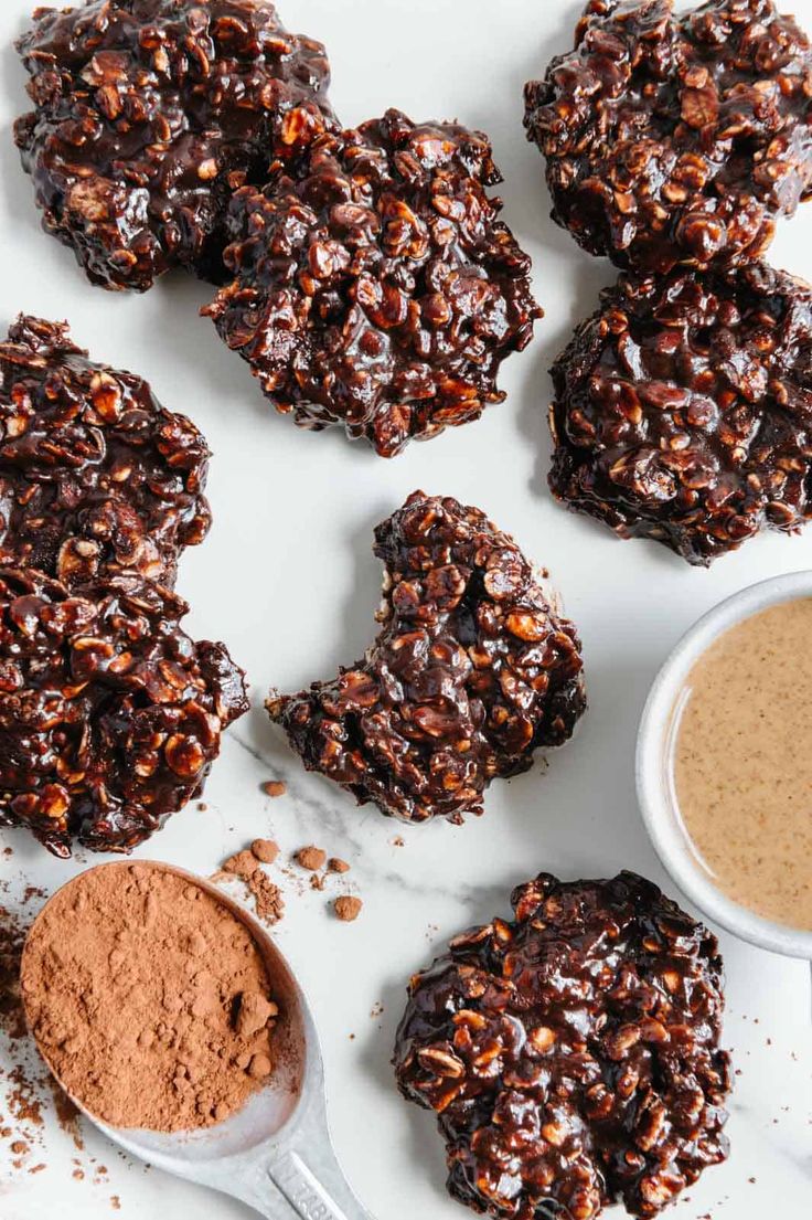 chocolate cookies and cocoa powder on a white surface with spoons next to them,