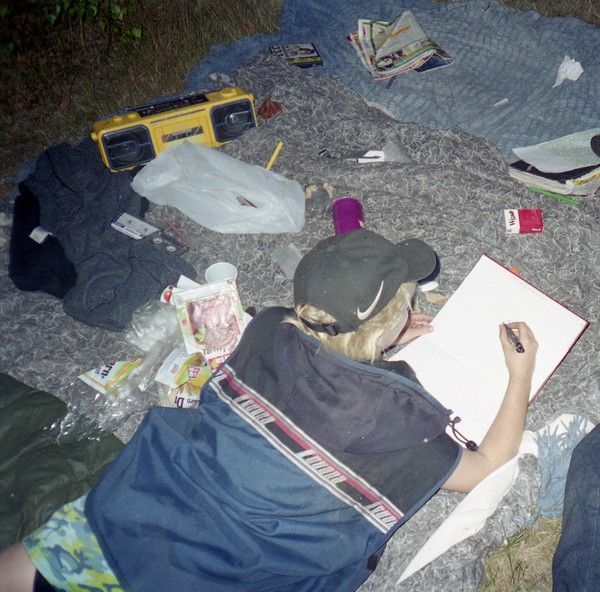 a person laying on top of a bed covered in blankets and writing with a pen