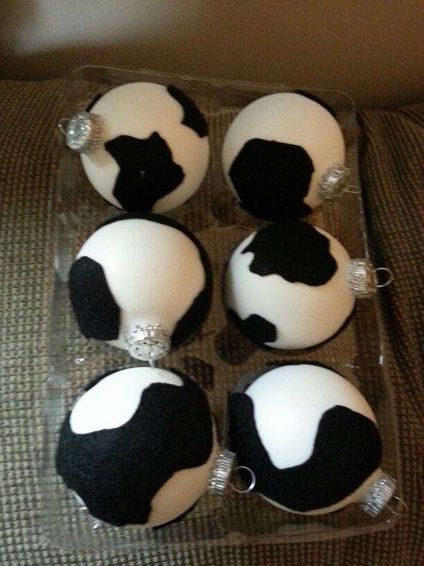 six decorated black and white christmas ornaments in a plastic container on a couch with a brown pillow