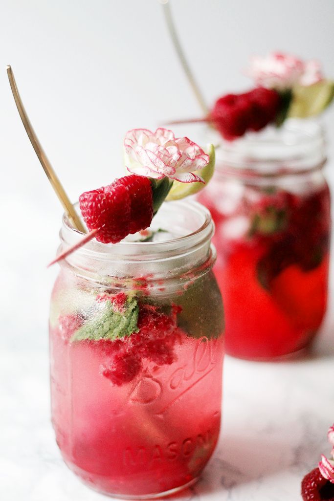 two mason jars filled with liquid and strawberries