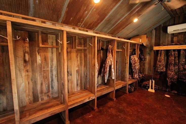 the inside of a wooden cabin with several coats hanging on racks and two benches in front of them