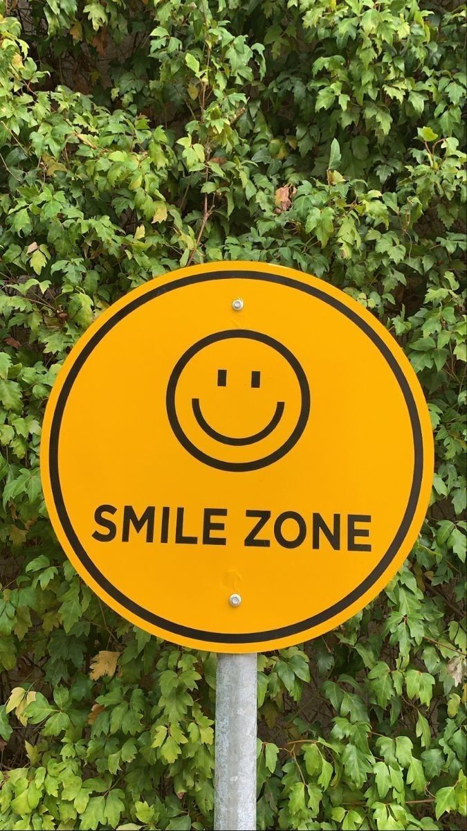 a yellow smile zone sign sitting in front of some bushes