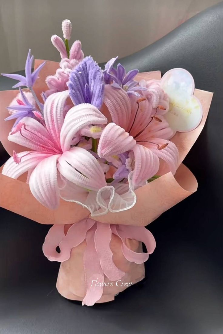 a bouquet of pink and purple flowers sitting on top of a black chair