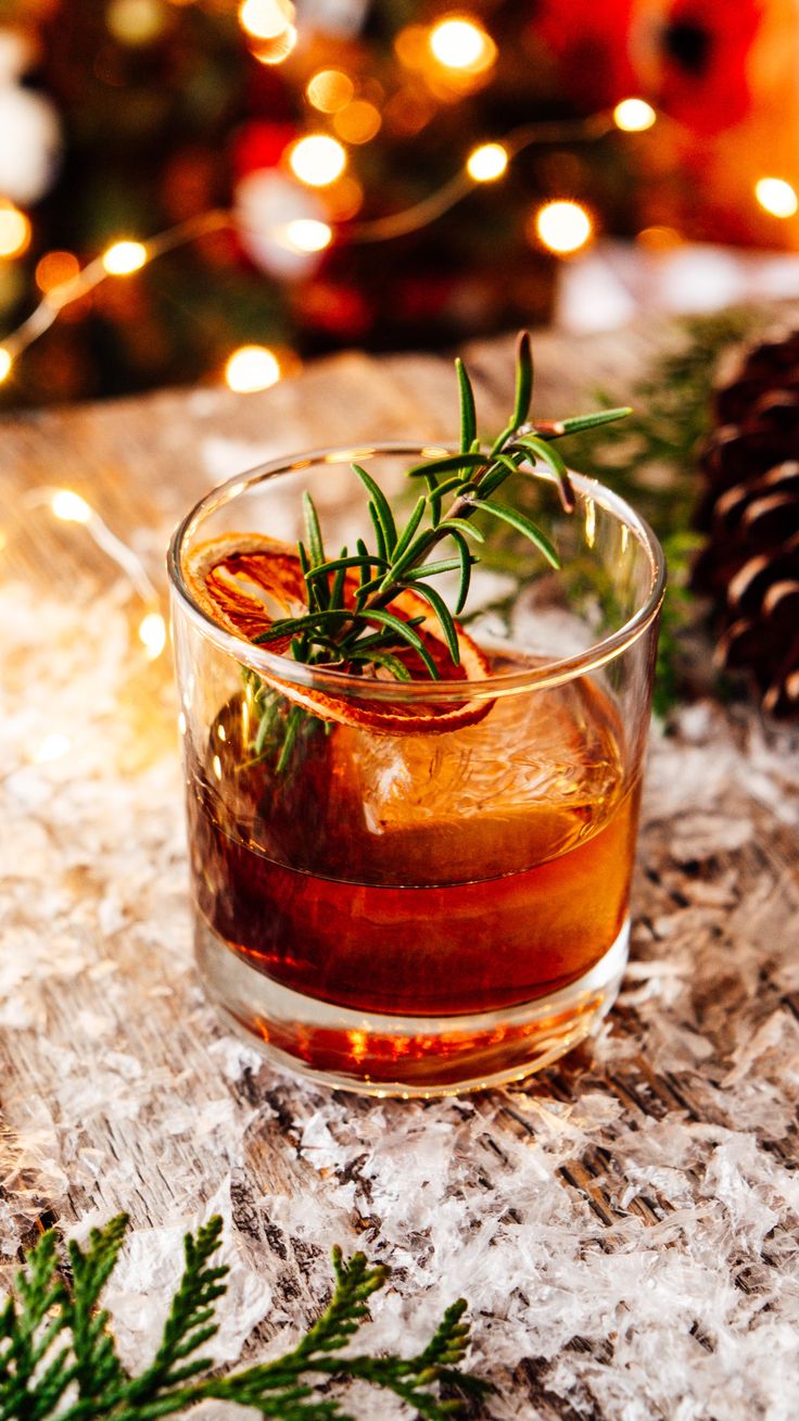 a glass filled with liquid sitting on top of a table next to a pine cone