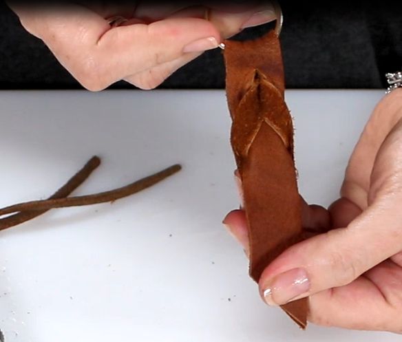 two hands are working on an object with leather