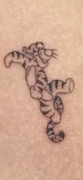 a small tiger tattoo on the back of a woman's shoulder