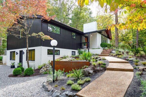 a modern house in the woods surrounded by trees and shrubs with steps leading up to it