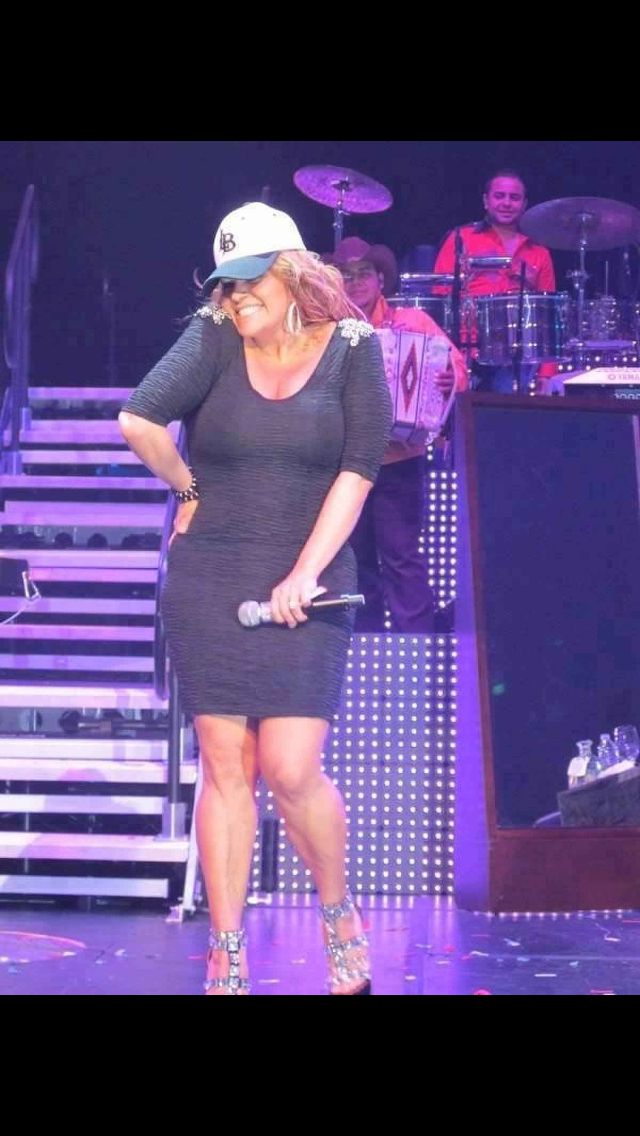 a woman standing on top of a stage wearing a hat and holding a microphone in her hand