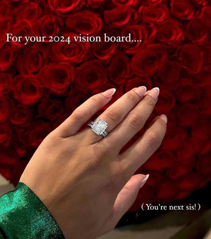 a woman's hand with a diamond ring on her finger and red roses in the background