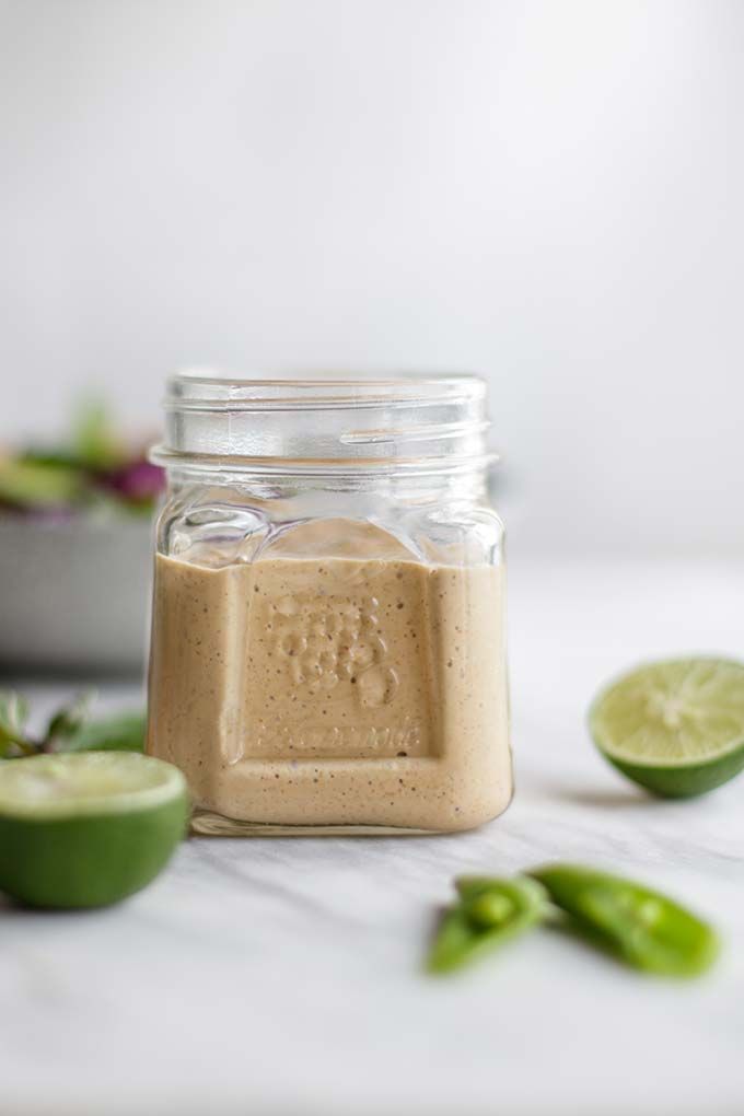 a jar filled with peanut butter next to sliced jalapenos and limes