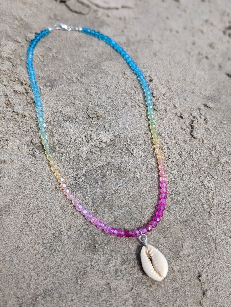 Our Tropical Shell Chokers Indulge in the essence of paradise with every wear! This Shell Choker brings a touch of tropical beauty to any outfit, making you feel like you're lounging on a remote island. Handcrafted with genuine shells, each choker is unique and radiates a luxurious, beachy vibe. Elevate your style and transport yourself to a beach getaway every time you put on this statement piece! Strung on durable jewelry cord, this Shell choker is adorned with rainbow faceted glass beads and a cowrie shell as the focal point and a sterling silver closure. These necklaces can be worn alone or stacked for a laid-back, tropical beachy feel. Dimensions: measuring 16 inches around (rainbow variations may vary) Add this one-of-a-kind necklace to your cart today and bring a touch of the ocean Colorful Beaded Shell-shaped Necklace For Beach, Multicolor Shell-shaped Jewelry For Beach, Strand Shell Beaded Necklaces For Beach Season, Beach Shell Necklace With Colorful Beads, Colorful Beads Shell Strand Necklace For Beach, Summer Shell Necklace With Colorful Beads, Colorful Beaded Strand Shell Necklace For Beach, Shell-shaped Beaded Necklaces For Beach, Multicolor Shell Jewelry For Vacation