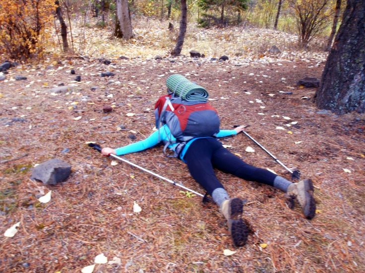 a person laying on the ground with skis and poles in their hands while wearing a backpack