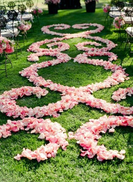 pink flowers are arranged in the shape of a heart on green grass at a wedding ceremony