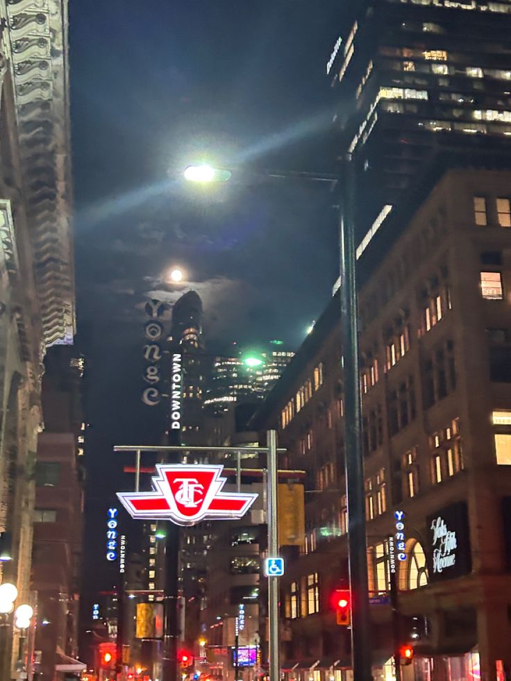 a city street at night with traffic lights and tall buildings in the backround