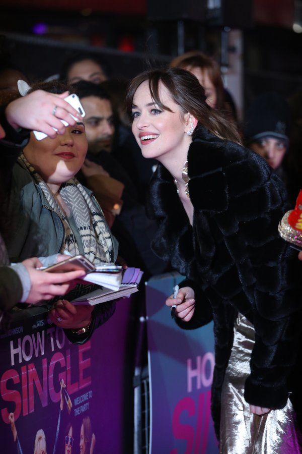 a woman in a black fur coat signing autographs for fans at the uk premiere of how to be single