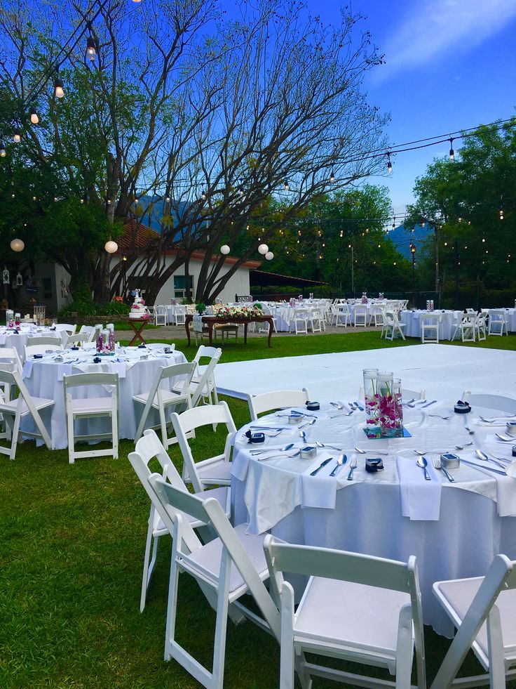 tables and chairs are set up for an outdoor wedding reception in the grass at dusk