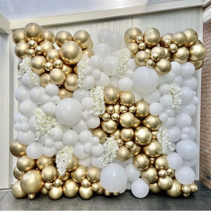 gold and white balloons are arranged on the wall