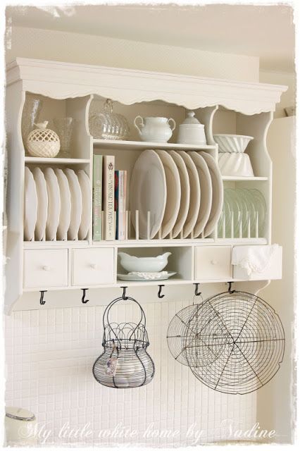 a white shelf filled with lots of plates and bowls