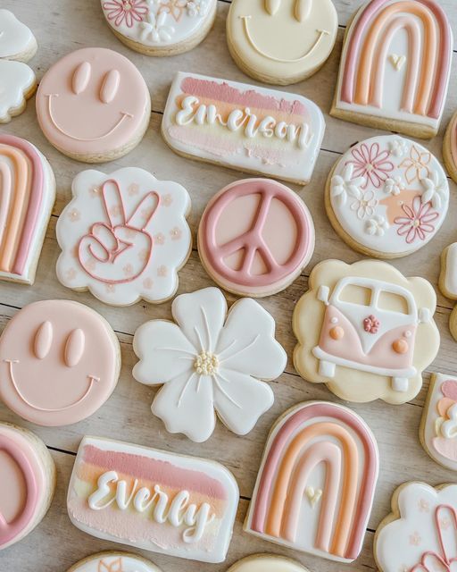 many decorated cookies with different designs and colors on a wooden surface, including peace, love, and rainbows