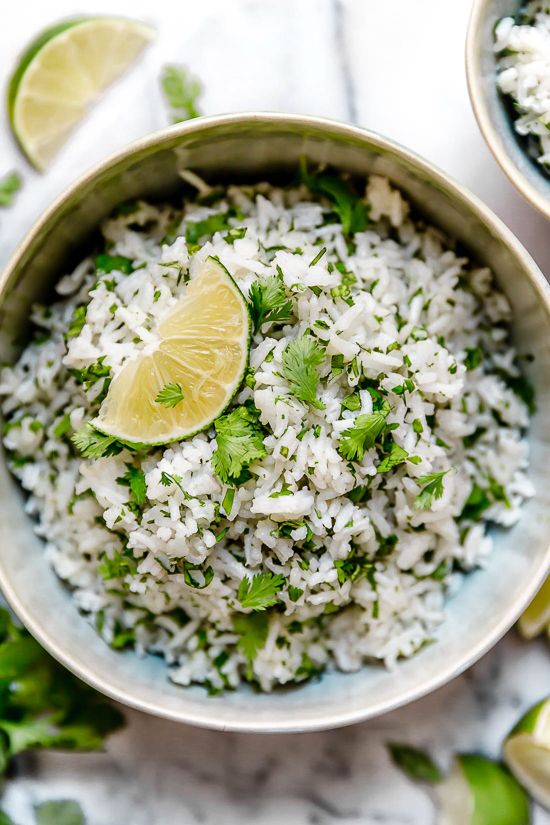 two bowls filled with rice, limes and cilantro