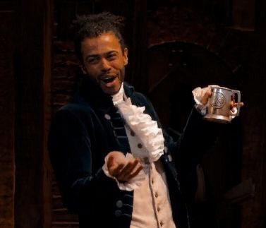 a man dressed in colonial clothing holding a beer