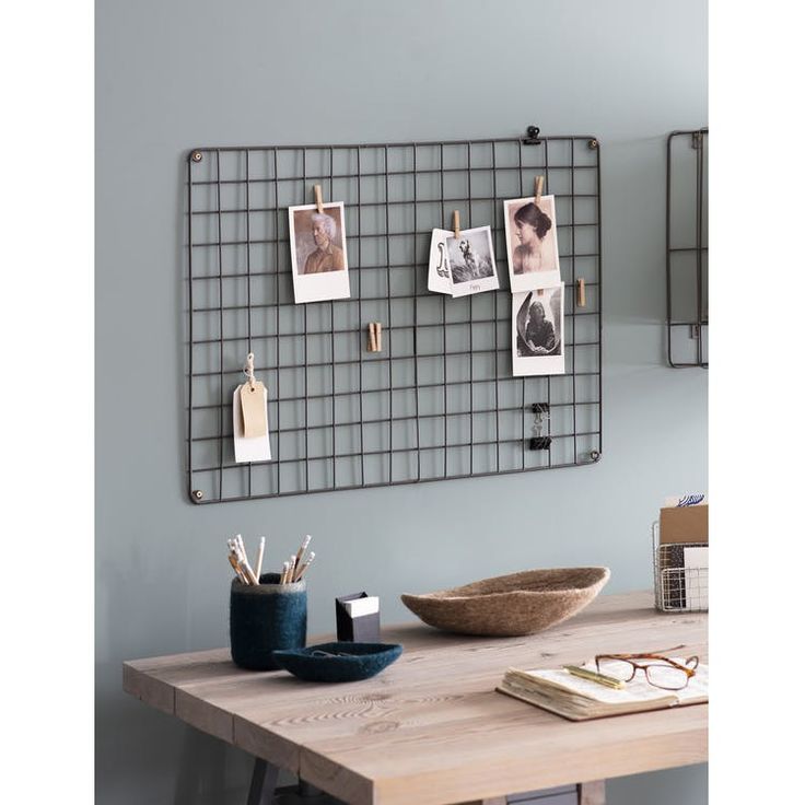 a wooden table topped with a metal grid wall mounted memo board