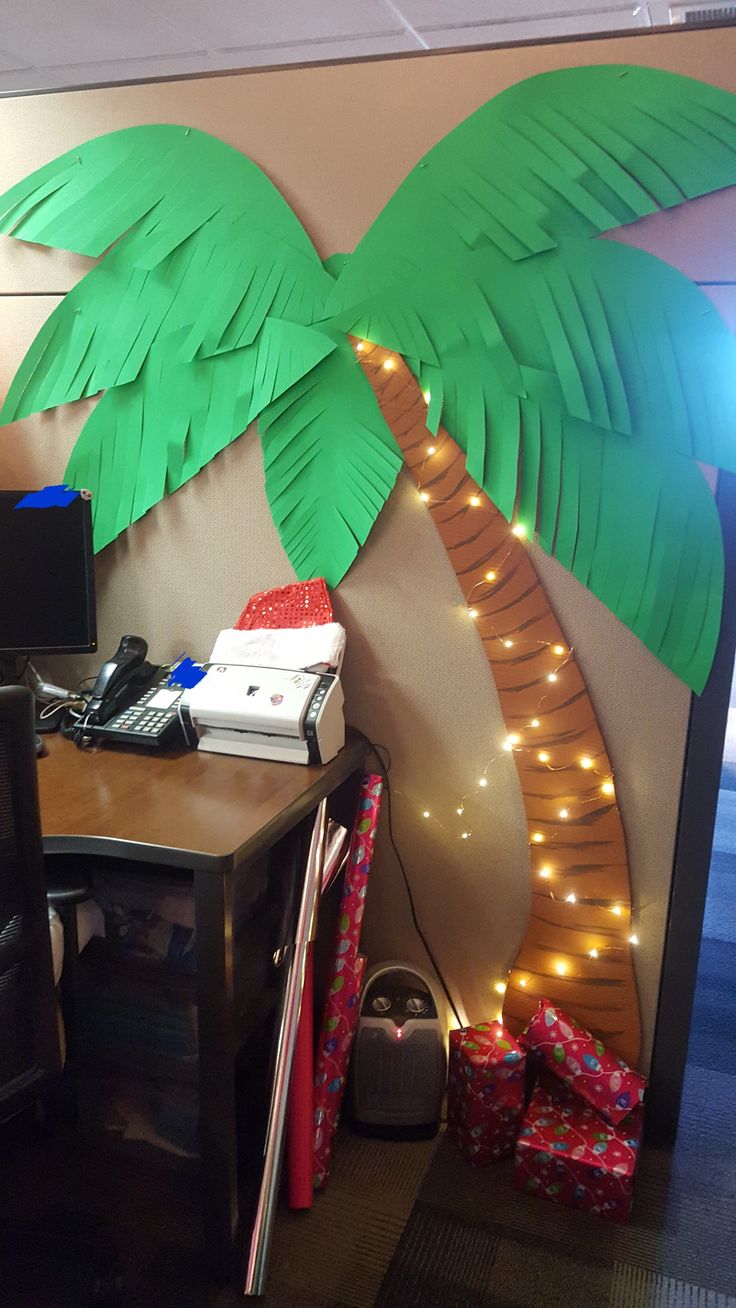 an office cubicle with a palm tree on the wall and lights strung from it