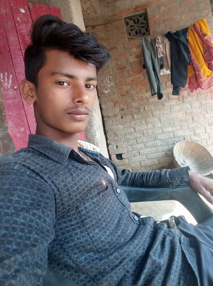 a young man sitting in front of a brick wall