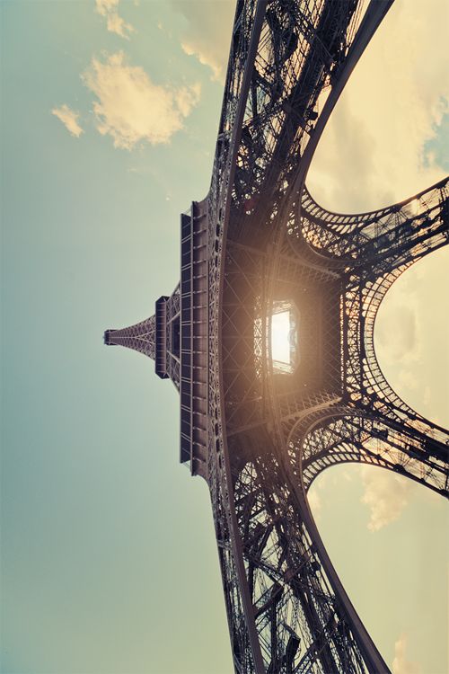 the eiffel tower in paris, france is seen from below as the sun peeks through the clouds