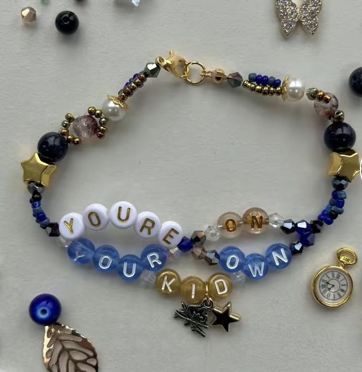 several bracelets with charms and beads on a white surface next to other jewelry items