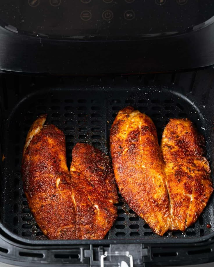 two pieces of chicken cooking in an air fryer