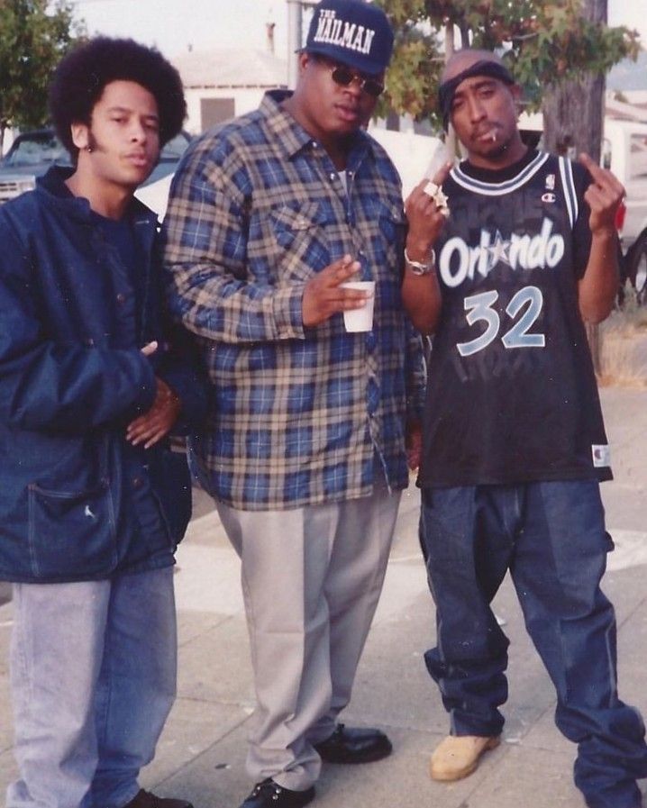 three young men standing next to each other on the sidewalk, one holding a drink