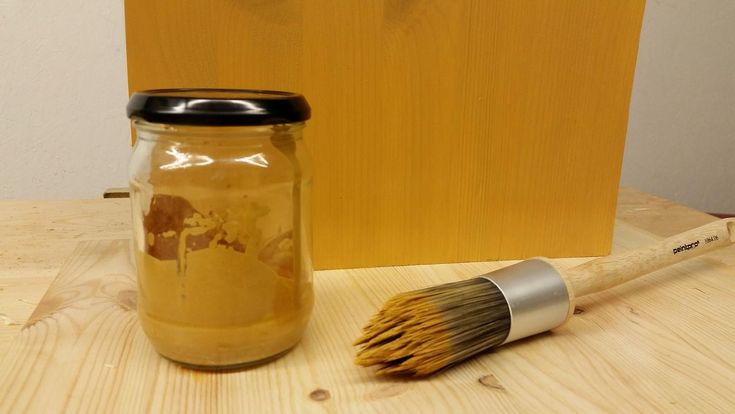 a wooden table topped with a jar filled with liquid and a brush